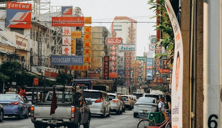Vibrant street view of Bangkok's Chinatown with colorful signs and traffic, showcasing urban life.